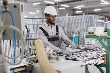 Factory worker handling aluminum profiles for windows and doors production