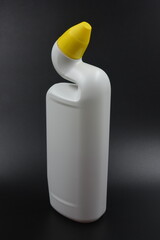 A white plastic bottle with a curved neck and a yellow cap is placed on a black plastic background....