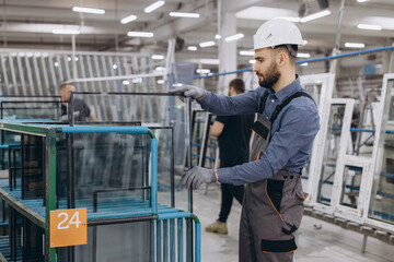 Factory worker handling glass pane for pvc windows production