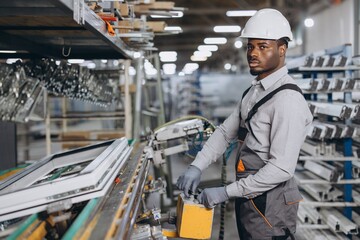 Factory worker operating machinery producing PVC windows and doors