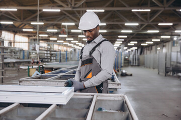 Factory worker assembling aluminum window frames on production line