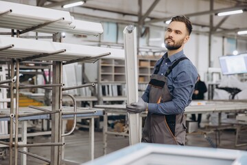 Factory worker carrying aluminum window frame in production line