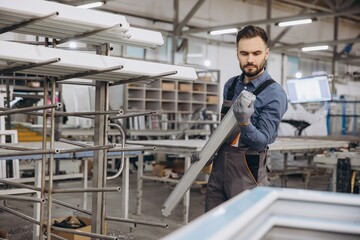 Factory worker holding aluminum window frame in production line