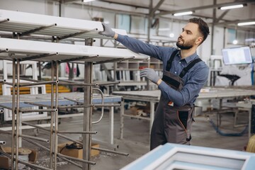 Factory worker storing aluminum window frames on metal rack