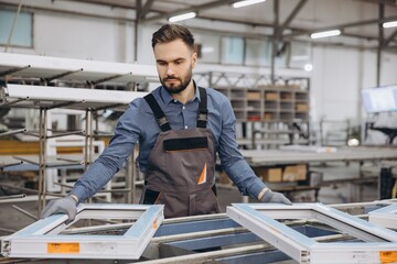 Factory worker assembling pvc windows in production line