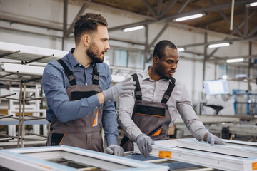 Factory workers assembling aluminum and pvc window frames in workshop