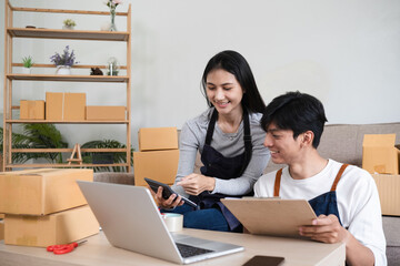 Obraz premium Young Couple Managing Online Business, Taking Orders, and Packing Products in a Modern Home Office Setting