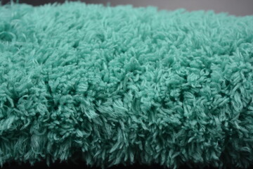 Beautiful green soft fluffy, nylon, synthetic fabric arranged on a black plastic background.
