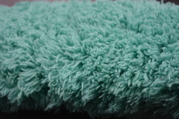 Beautiful green soft fluffy, nylon, synthetic fabric arranged on a black plastic background.