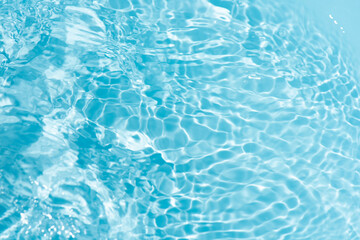 Blue water with ripples on the surface. Defocus blurred transparent blue colored clear calm water surface texture with splashes and bubbles. Water waves with shining pattern texture background.