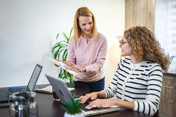 Two female colleagues working together on business report