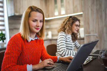 Two female colleagues at a desk working on laptop