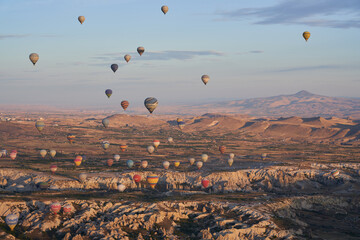 Hot air balloons flying over rock formations in Cappadocia, Turkey