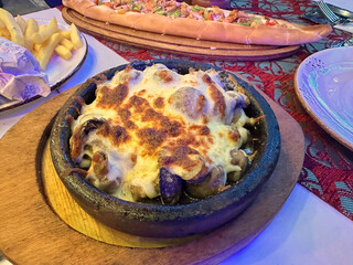 Baked mushrooms with melted cheese in a rustic dish on a table with assorted food