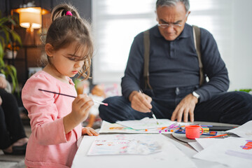 Grandpa and granddaughter enjoy painting together