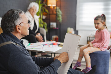 Grandfather drawing his granddaughter at home