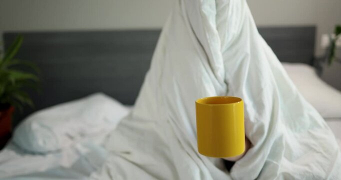 A playful figure is nestled under a soft white blanket, creating a cozy atmosphere in a modern bedroom