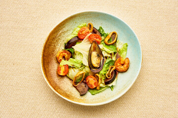 A bowl of food with a variety of ingredients including shrimp, tomatoes