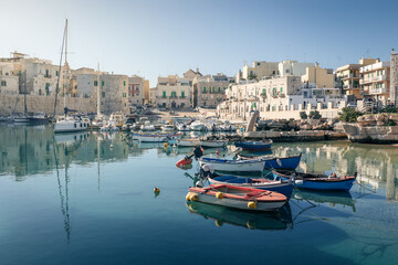 Obraz premium Fishing boat in old harbour of ancient mediterranean town with stone buildings, Giovinazzo, Italy