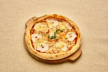 A pizza with a crust and toppings including apples and herbs