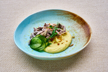 A blue plate with a white sauce and a green vegetable on top