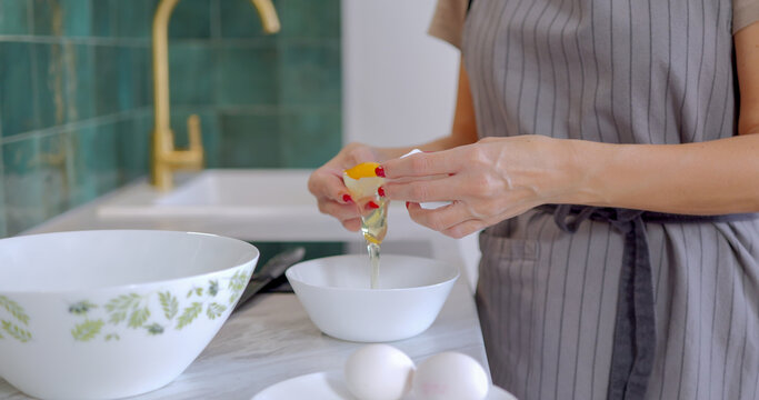 Woman in Gray Apron Cracking Fresh Egg in Kitchen