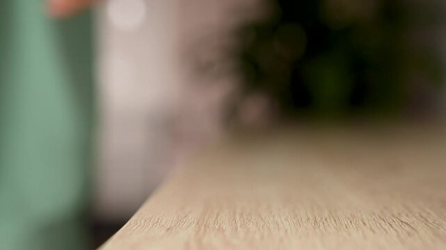 Woman hand puts mobile phone on wooden desk, close-up. Putting down cellphone on wooden table