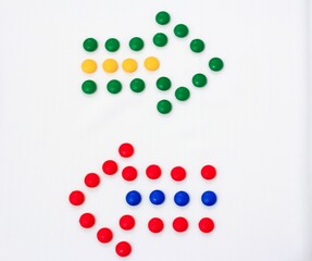 Two colorful arrows made from candy pieces on a white background, symbolizing direction, choice, or contrast in vibrant design