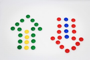 Up and down arrows created with colorful candy dots on a white background, representing direction, choice, and balance