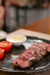 Medium rare striploin steak served on plate with tomato and lemon