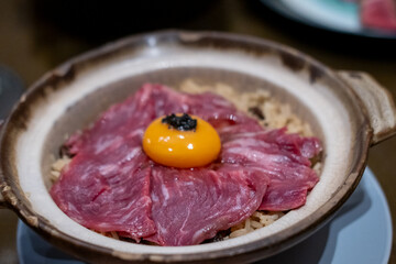 Beef fat fried rice in a bowl, with sliced meat and egg yolk on top
