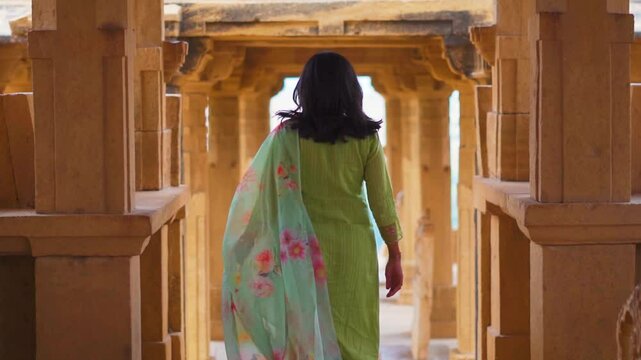 Indian girl exploring architecture of Bada Bagh cenotaphs in Jaisalmer, Rajasthan, India. Tourist on vacation. Travel, history, ancient architecture concept.