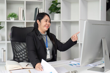 Successful Businesswoman Working on Computer in Modern Office Setting with Documents and Charts