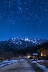 Fototapeta premium Beautiful night landscape with starry sky over snowy mountain and village road