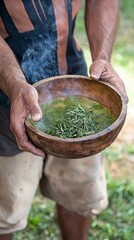 Hands hold a wooden bowl filled with fresh herbs in a natural setting, showcasing traditional practices and ingredients