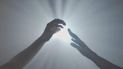 Hand silhouettes, man and woman hands touching and crossing fingers against bright white colored spotlight, isolated on studio background close up shot.