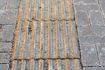 Tactile tiles covered with salt and sand mixture for deicing, ensuring safety on slippery paving...