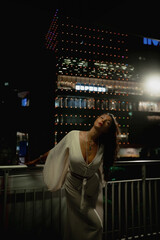 Young caucasian female posing at night with vibrant city lights