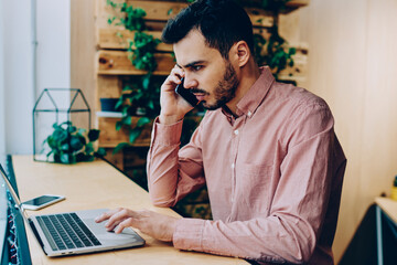 Annoyed male making telephone call to operator helpline having problem with software on laptop...
