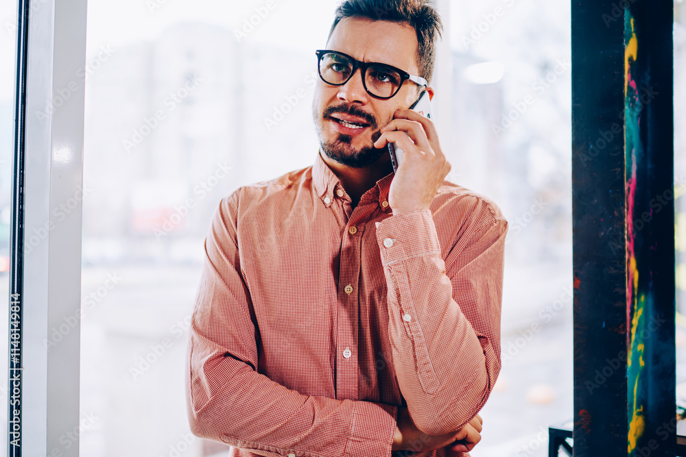 Aufkleber male businessman making dissatisfied face while talking with service operator on mobile phone, young
