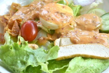 fresh vegetable topping boiled egg topping crispy fried taro dressing Indian sauce salad on plate 