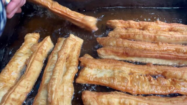 cooking Chinese deep-fried dough stick (also called youtiao). Famous traditional snack in China