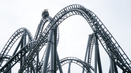 Rollercoaster track ascending a steep curve against a bright sky.