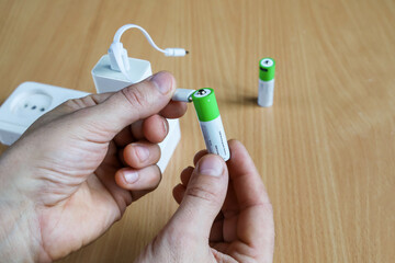 Turn on USB plug, Rechargeable battery in hands, charging from the power adapter, Textured surface