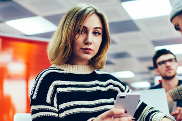 Portrait of professional female designer with short haircut looking at camera while checking mail...