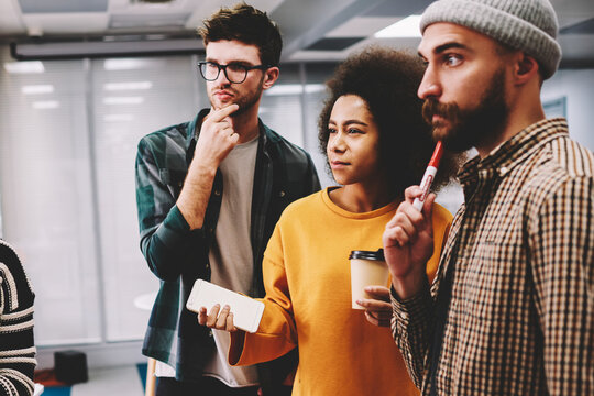 Diversity group of pondering students thinking on solution during brainstorming in university interior.Contemplative multicultural hipster guys teamworking on solving issues in office