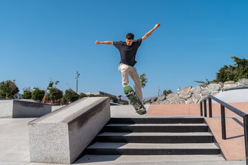 young skater wearing black tshirt jumps a staircase in a skate park. 