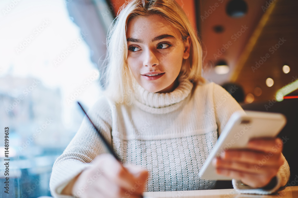 Poster clever female student doing homework task in cafe interior holding smartphone for networking,creativ
