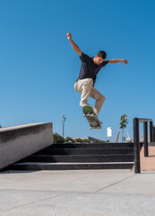 young skater wearing black tshirt jumps a staircase in a sunny day. movement 1