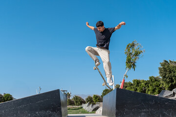 young skater wearing black tshirt jumping a pyramid ramp in Arinaga skate park. 